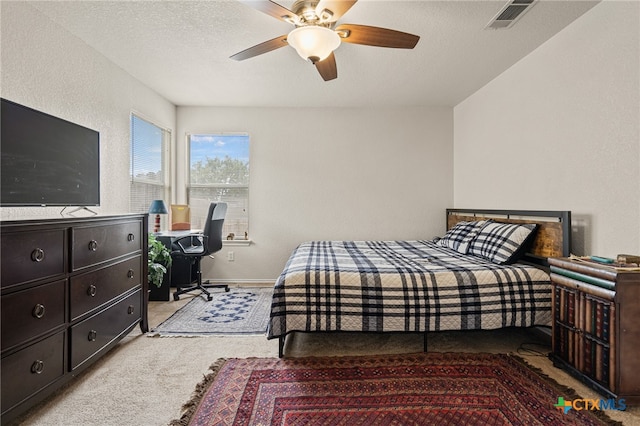 carpeted bedroom featuring ceiling fan and a textured ceiling