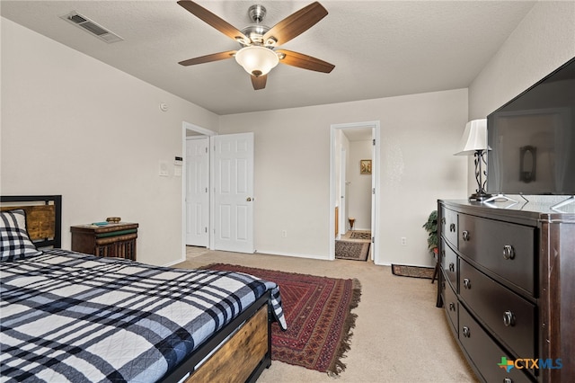 bedroom featuring ceiling fan, a textured ceiling, and light colored carpet