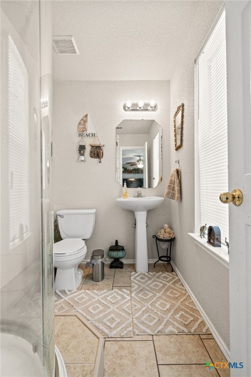 bathroom featuring tile patterned flooring, an enclosed shower, a textured ceiling, and toilet