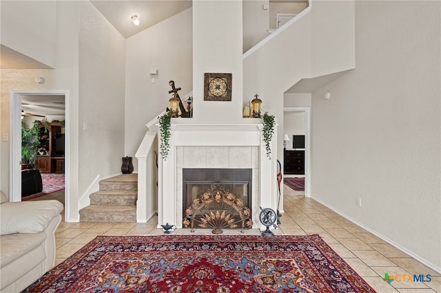 living room featuring a tiled fireplace, light tile patterned floors, and high vaulted ceiling