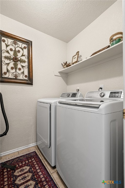 washroom with a textured ceiling, light tile patterned floors, and separate washer and dryer