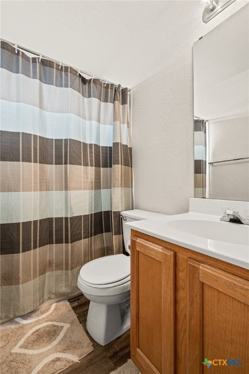 bathroom featuring toilet, vanity, hardwood / wood-style flooring, and curtained shower