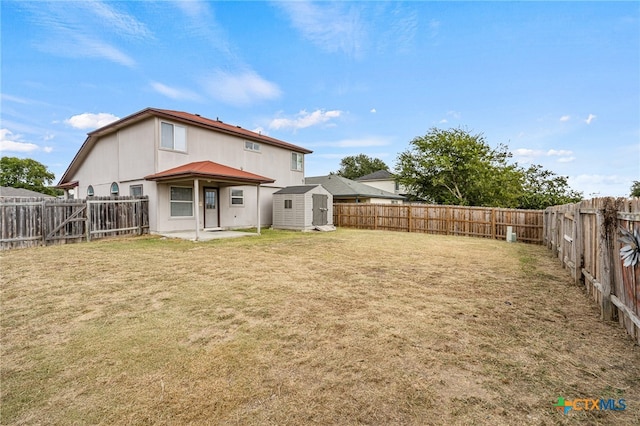 rear view of property featuring a shed and a yard