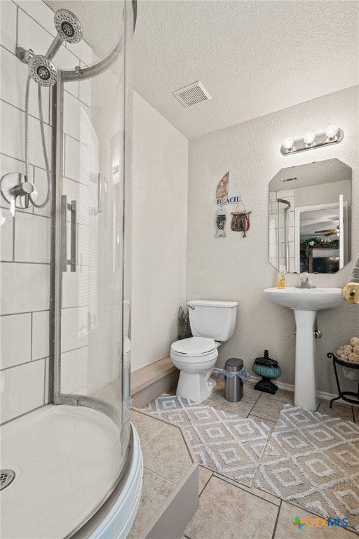 bathroom with a shower with shower door, a textured ceiling, toilet, and tile patterned floors