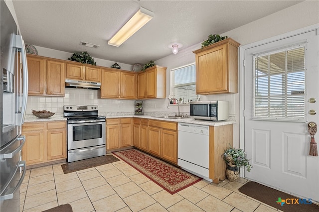 kitchen with stainless steel appliances, a textured ceiling, sink, tasteful backsplash, and light tile patterned floors