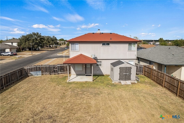 back of house featuring a patio, a yard, and a storage unit