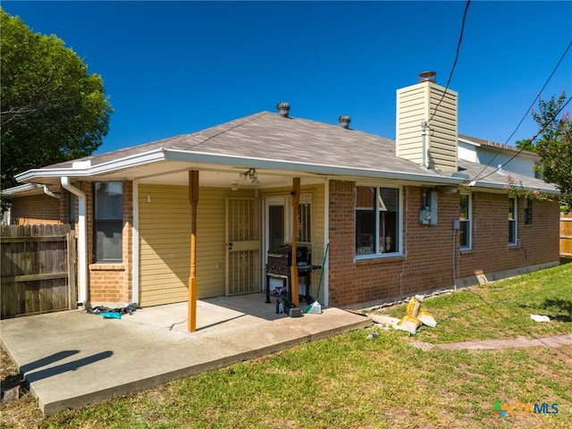 rear view of property with ceiling fan, a yard, and a patio