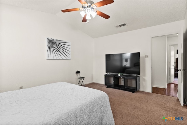 bedroom featuring ceiling fan, a textured ceiling, vaulted ceiling, and dark carpet