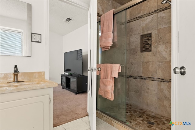 bathroom with vanity, a textured ceiling, tile patterned flooring, and a shower with shower door