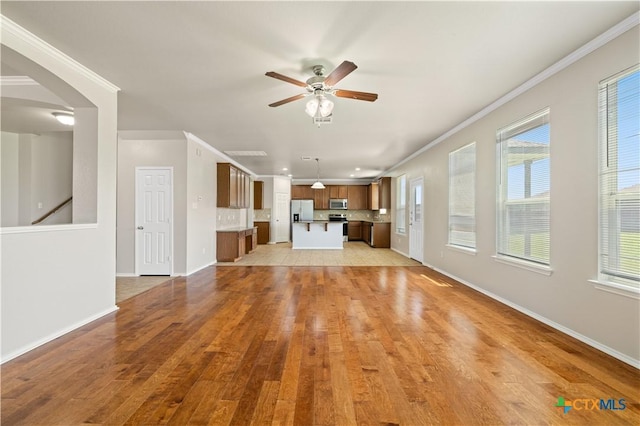2523 Red Fern Dr, Harker Heights, TX 76548 - unfurnished living room featuring ceiling fan, light wood-type flooring, crown molding, and arched walkways