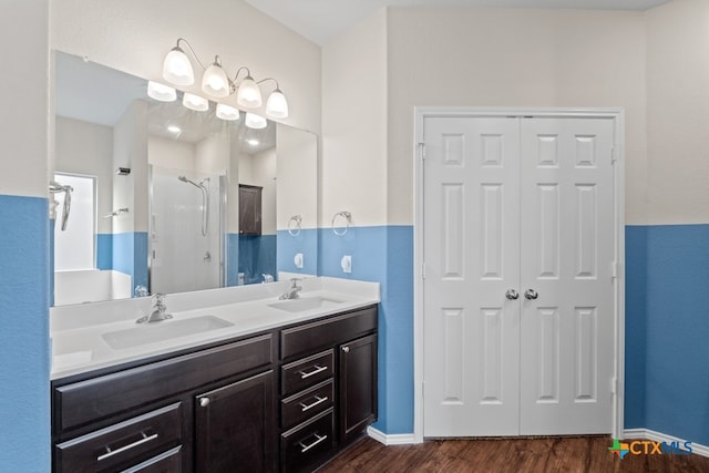 full bathroom with double vanity, wood finished floors, a sink, and a shower stall