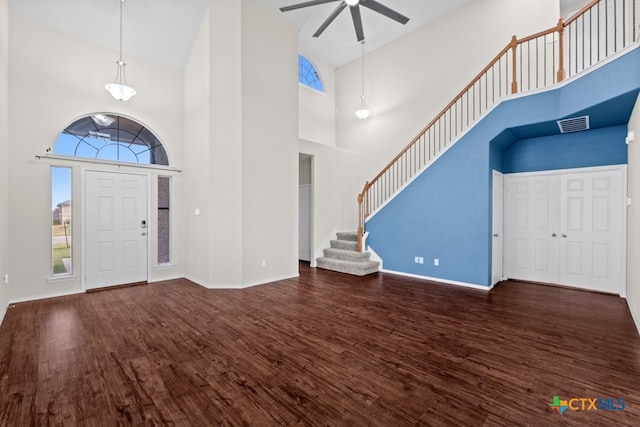 foyer entrance featuring baseboards, ceiling fan, stairway, dark wood-style flooring, and a high ceiling