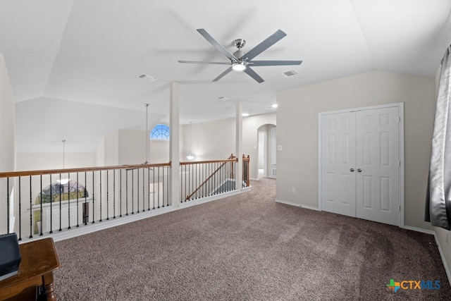 unfurnished room featuring lofted ceiling, carpet, visible vents, and arched walkways