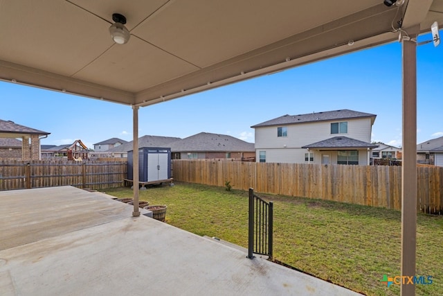 view of patio / terrace with ceiling fan, a fenced backyard, a residential view, an outbuilding, and a shed