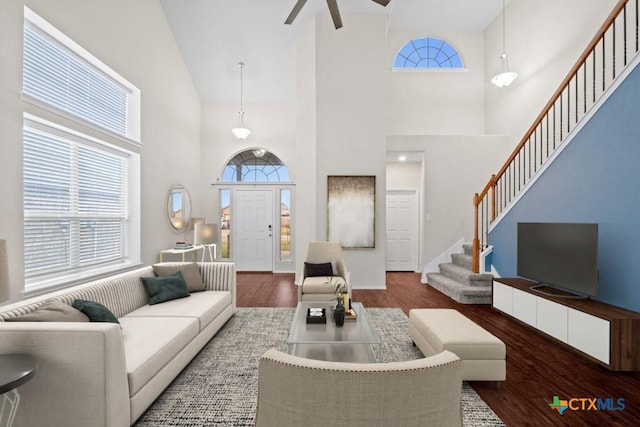 living area featuring a ceiling fan, a healthy amount of sunlight, stairway, and wood finished floors