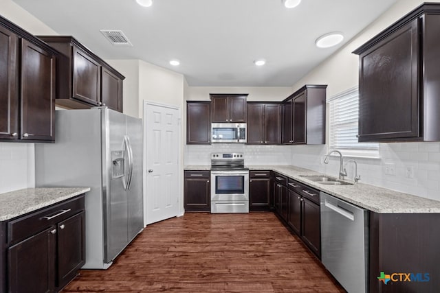 kitchen featuring light stone counters, a sink, visible vents, appliances with stainless steel finishes, and dark wood finished floors