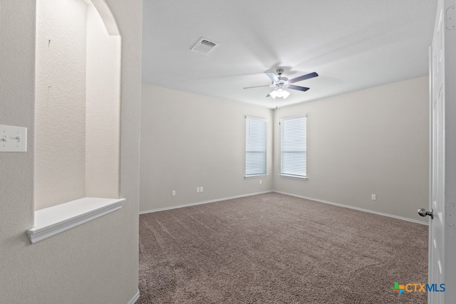 carpeted empty room featuring ceiling fan, visible vents, and baseboards