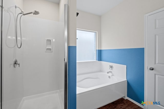 full bath featuring a stall shower, a garden tub, and wood finished floors