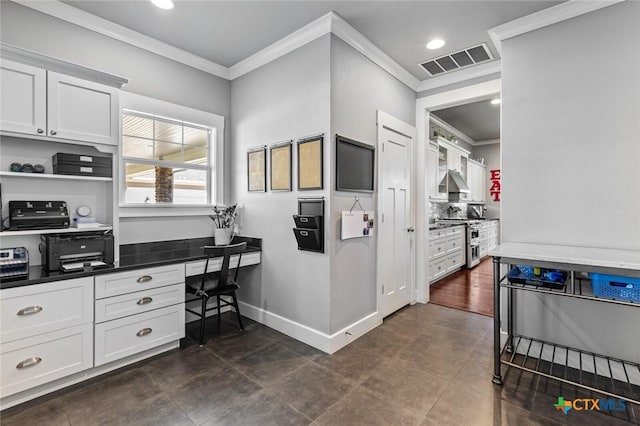 kitchen featuring ornamental molding, built in desk, white cabinets, and range with two ovens