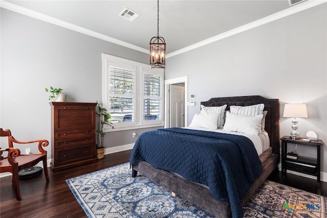 bedroom with dark wood-type flooring, crown molding, and a notable chandelier