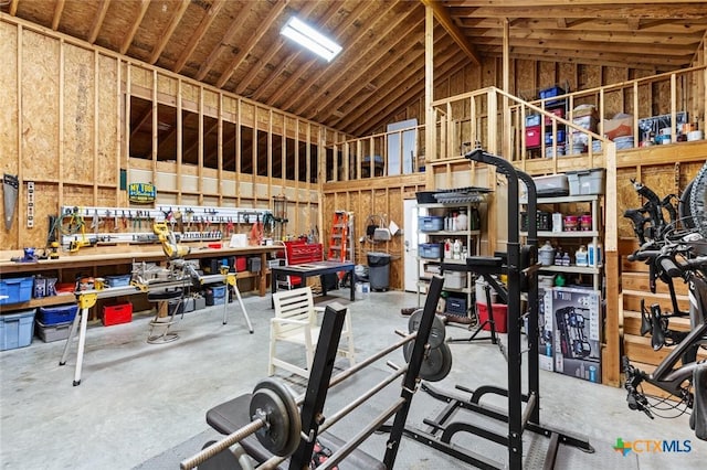 interior space featuring high vaulted ceiling, a workshop area, and concrete flooring