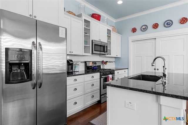 kitchen with white cabinets, appliances with stainless steel finishes, dark stone countertops, sink, and ornamental molding