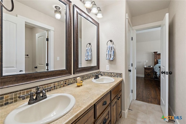 428 Colorado Dr, Cedar Creek, TX 78612 - ensuite bathroom with double vanity, decorative backsplash, tile patterned floors, and baseboards