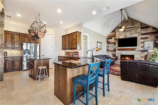 428 Colorado Dr, Cedar Creek, TX 78612 - kitchen featuring stainless steel fridge with ice dispenser, a center island, a breakfast bar area, a sink, and decorative backsplash