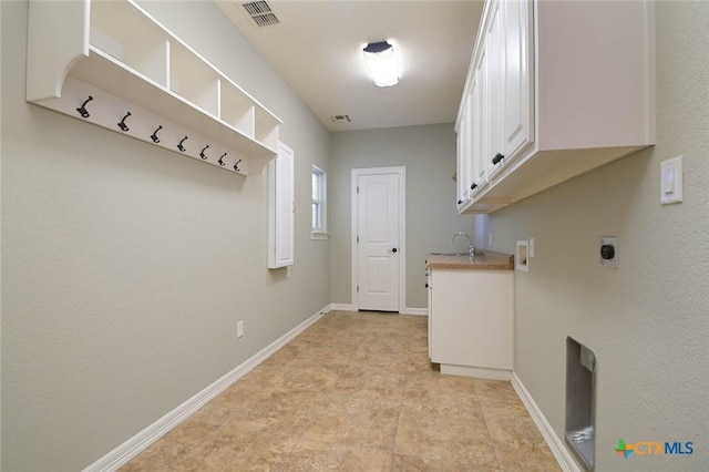 clothes washing area featuring sink, electric dryer hookup, and cabinets