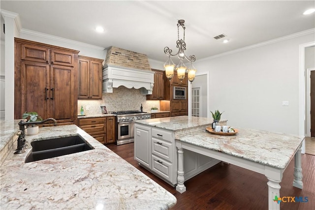 kitchen featuring light stone countertops, a kitchen island, backsplash, appliances with stainless steel finishes, and sink