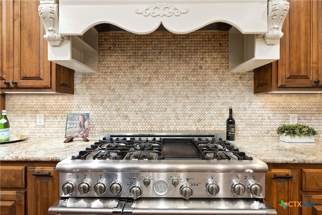 kitchen featuring custom exhaust hood, stainless steel range, decorative backsplash, and light stone countertops