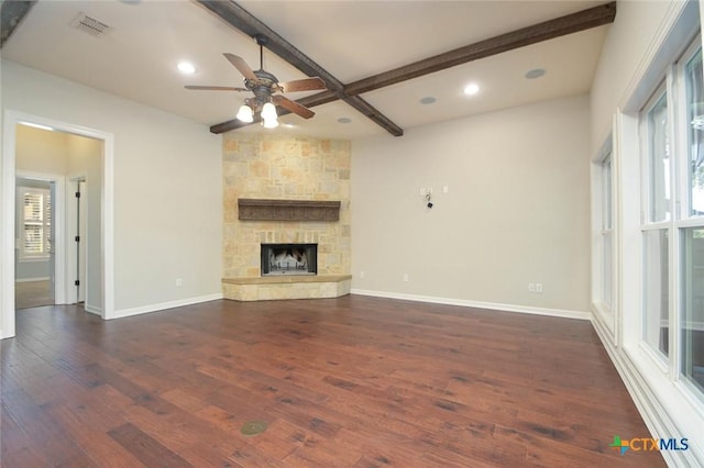 unfurnished living room with a stone fireplace, coffered ceiling, beamed ceiling, ceiling fan, and dark wood-type flooring