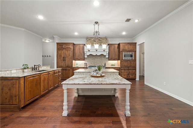 kitchen with stainless steel microwave, light stone countertops, hanging light fixtures, a kitchen bar, and dark hardwood / wood-style flooring