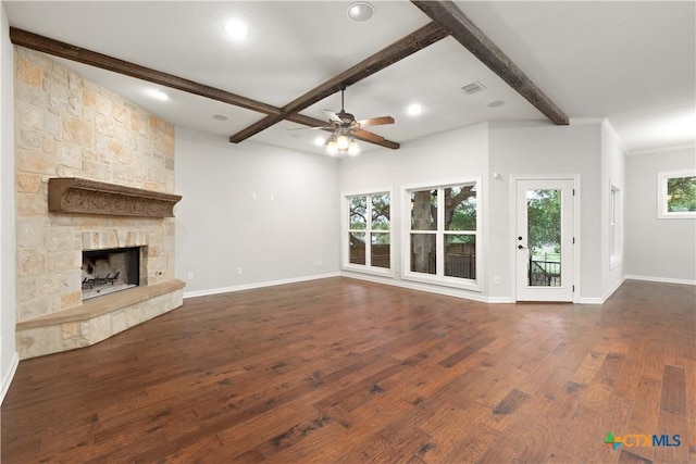 unfurnished living room with a fireplace, ceiling fan, beamed ceiling, and plenty of natural light