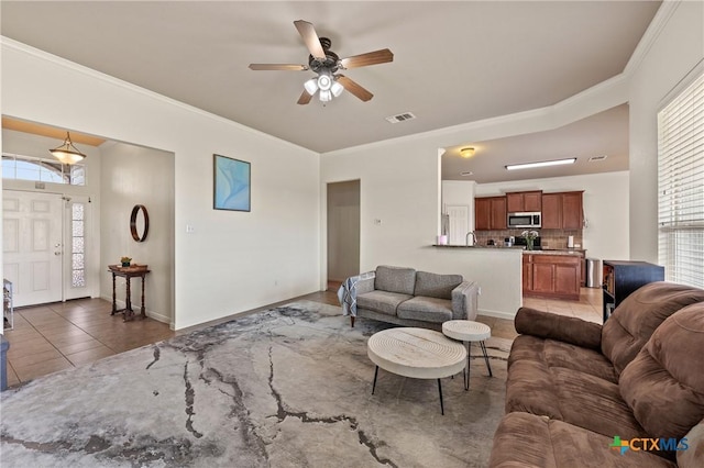 tiled living room featuring ceiling fan, a healthy amount of sunlight, and ornamental molding