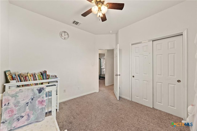 bedroom featuring light colored carpet, ceiling fan, and a closet