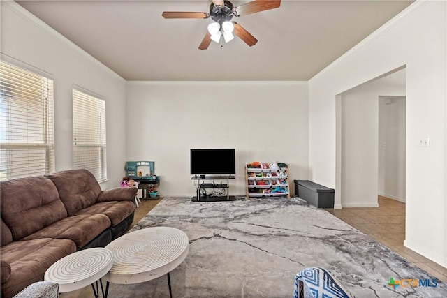 tiled living room with ornamental molding and ceiling fan