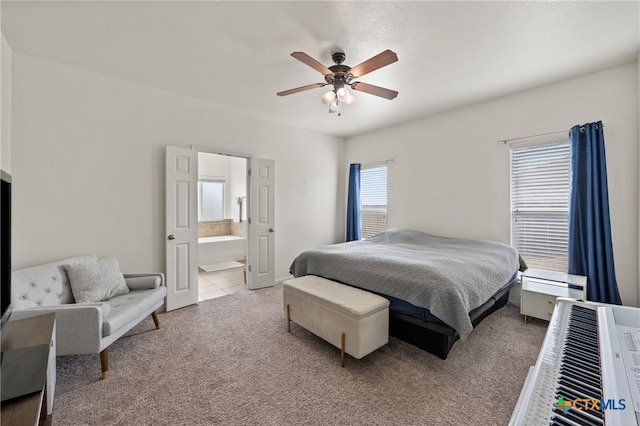 bedroom featuring connected bathroom, light colored carpet, and ceiling fan