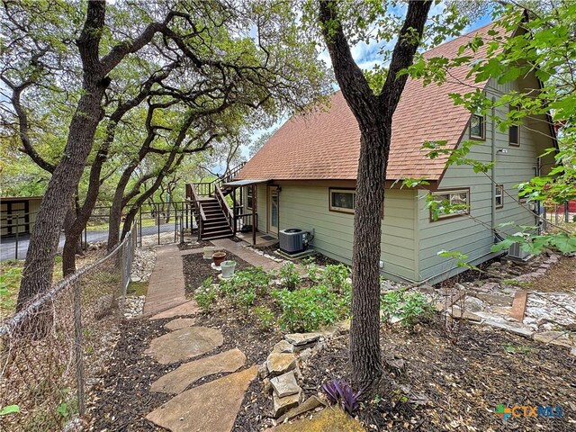 209 Lake Frst, Canyon Lake, TX 78133 - rear view of house with roof with shingles, central AC, stairway, and fence