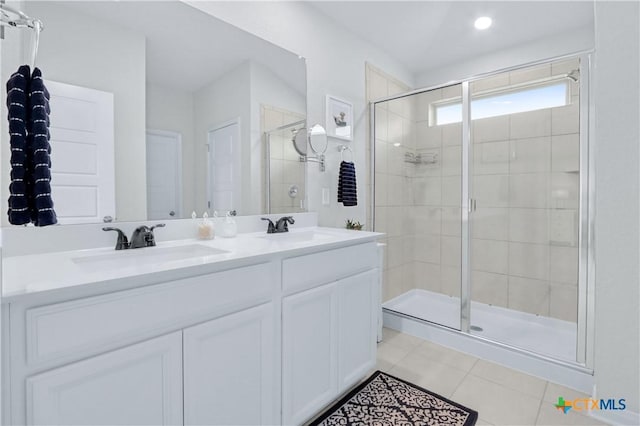 bathroom featuring a sink, double vanity, a shower stall, and tile patterned flooring