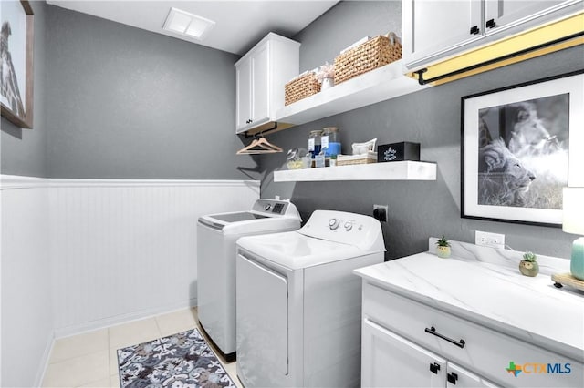 washroom featuring visible vents, a wainscoted wall, light tile patterned floors, washer and dryer, and cabinet space