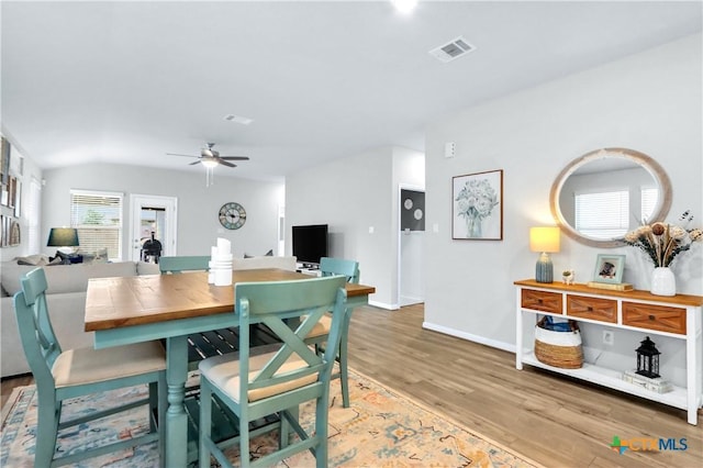 dining area with visible vents, baseboards, ceiling fan, lofted ceiling, and light wood-style flooring