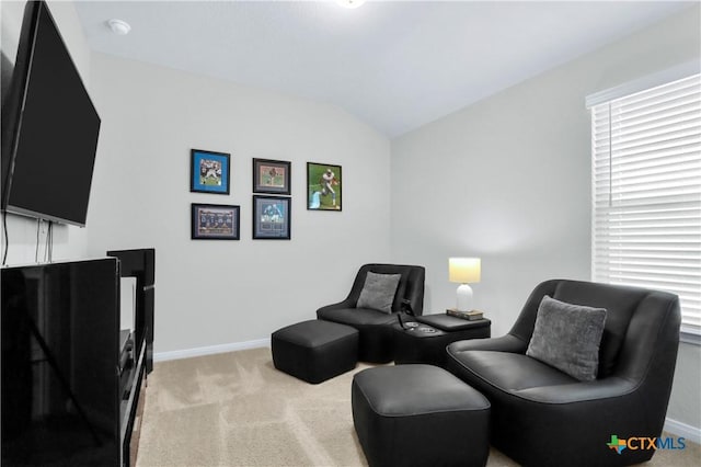 sitting room featuring baseboards, lofted ceiling, and light colored carpet