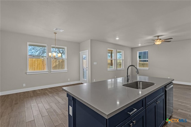 kitchen featuring sink, stainless steel dishwasher, ceiling fan with notable chandelier, dark hardwood / wood-style floors, and a center island with sink