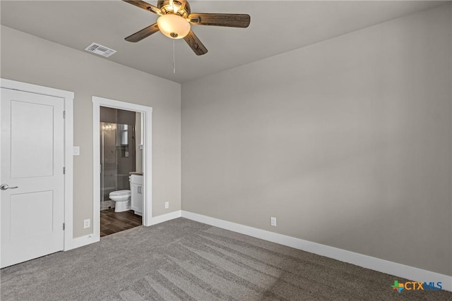 unfurnished bedroom with dark colored carpet, ceiling fan, and connected bathroom