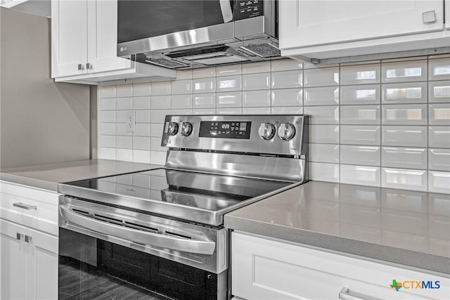 kitchen with stainless steel appliances, white cabinets, and tasteful backsplash