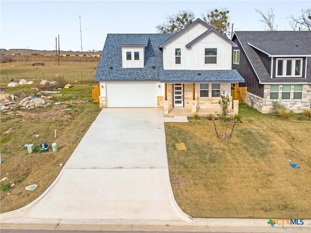 view of front of property featuring a garage, covered porch, and a front lawn