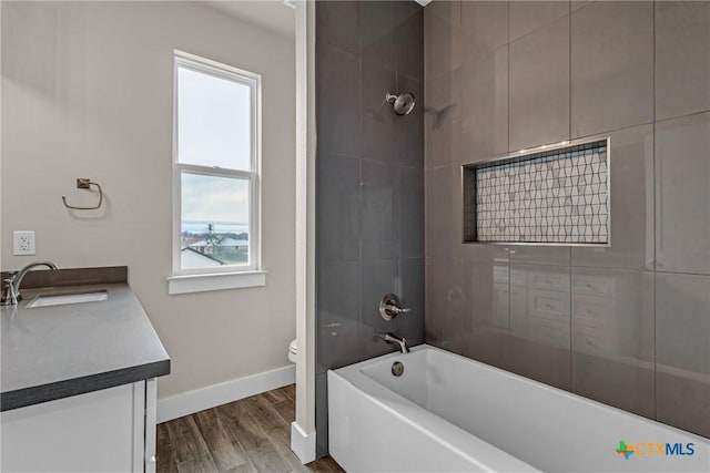 full bathroom featuring toilet, wood-type flooring, vanity, and tiled shower / bath