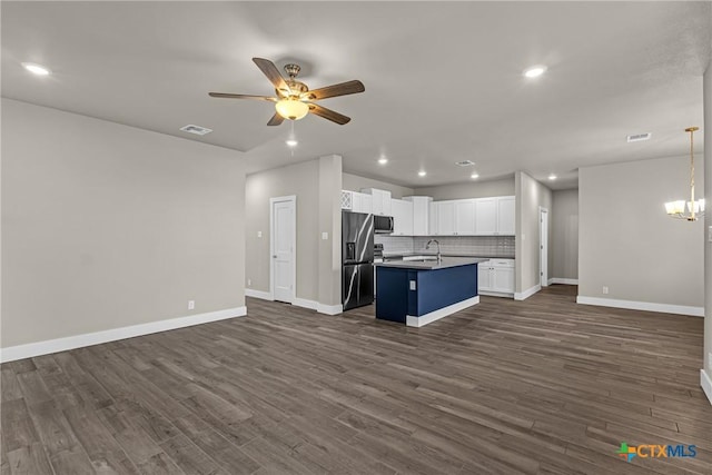 kitchen with stainless steel appliances, white cabinetry, ceiling fan with notable chandelier, backsplash, and a kitchen island with sink