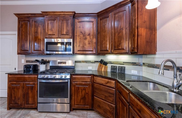 kitchen with appliances with stainless steel finishes, sink, backsplash, and dark stone counters